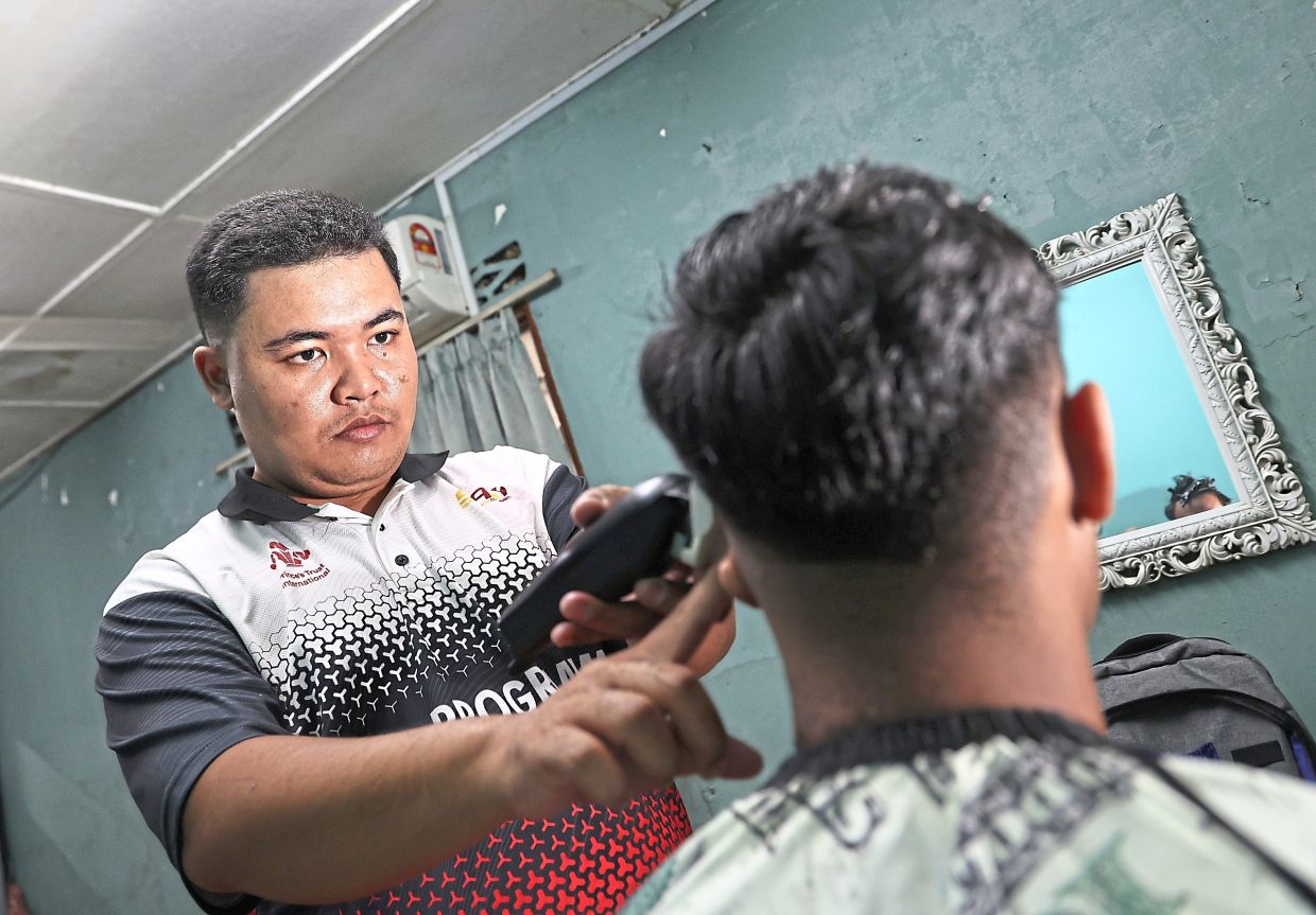 Muhammad Syafie earning an income giving haircuts from his home in Puchong.