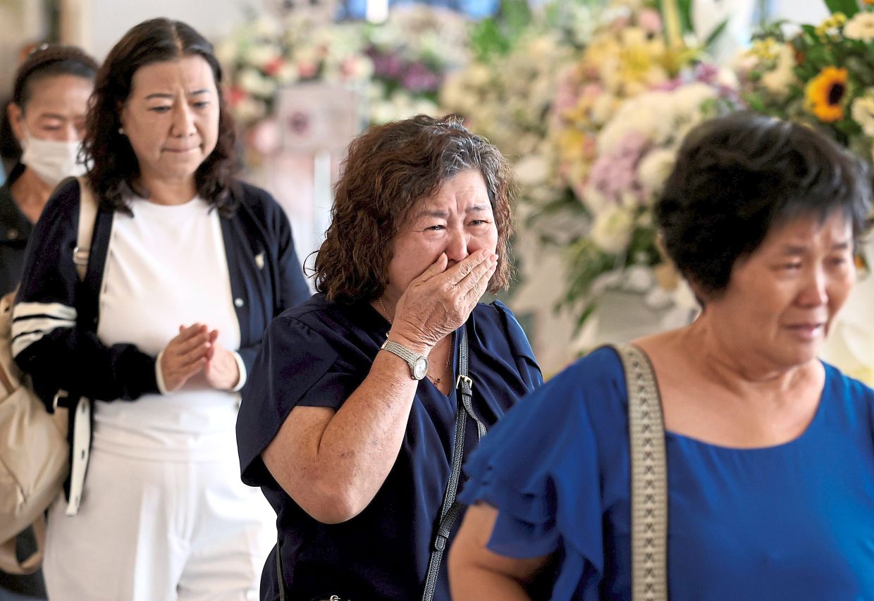 Grief-stricken: A mourner breaking down in tears after paying her respects to the late teenager.
