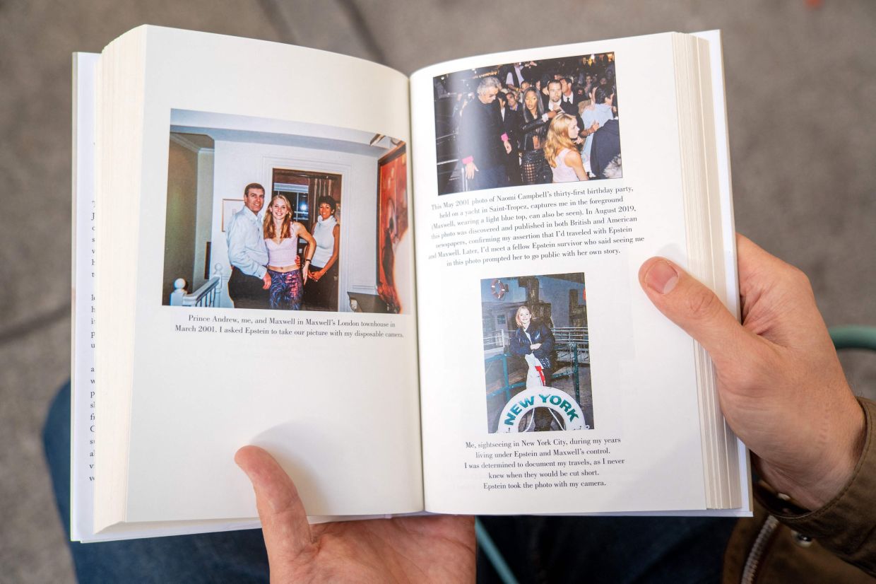 A person holds open pages of the book 'Nobody's Girl - A Memoir Of Surviving Abuse And Fighting For Justice' by Virginia Roberts Giuffre, displaying photos published in the book, as it is pictured in central London on Oct 21, 2025, on the day of its release in Britian. Photo: AFP