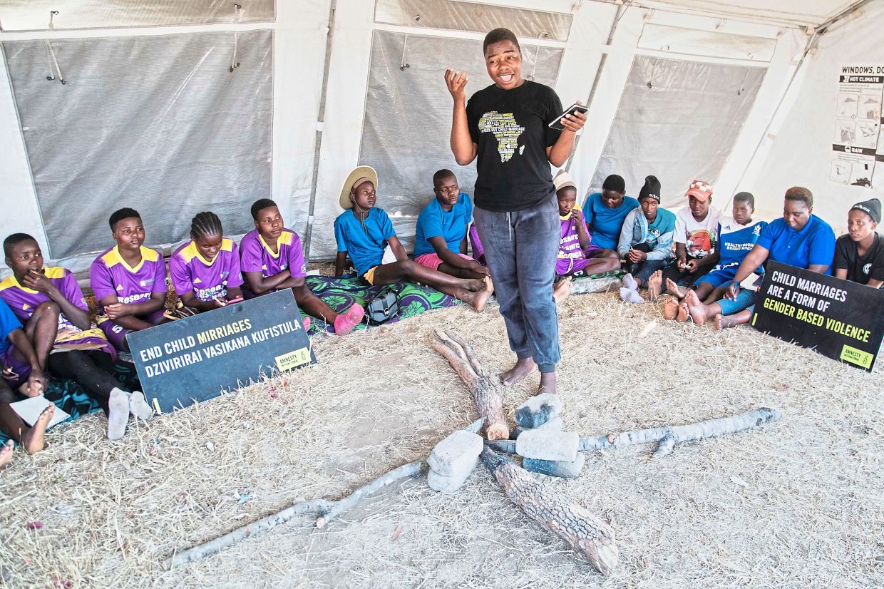 Women and girls sit inside a tent as a speaker talks about child marriage. Photo: AP