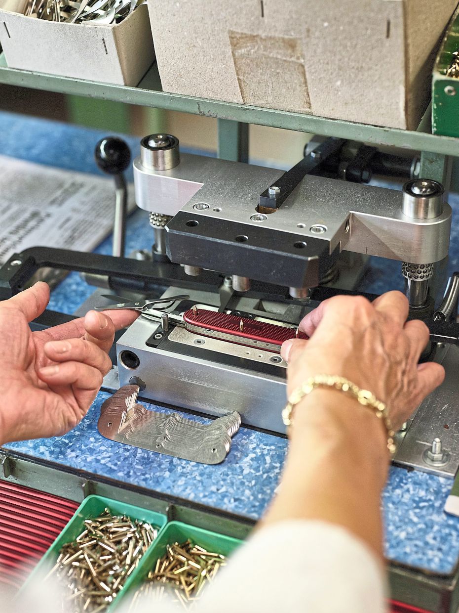 An employee assembling a knife at the Victorinox Swiss Army knife factory in Ibach-Schwyz, Switzerland. — Lea Meienberg/The New York Times