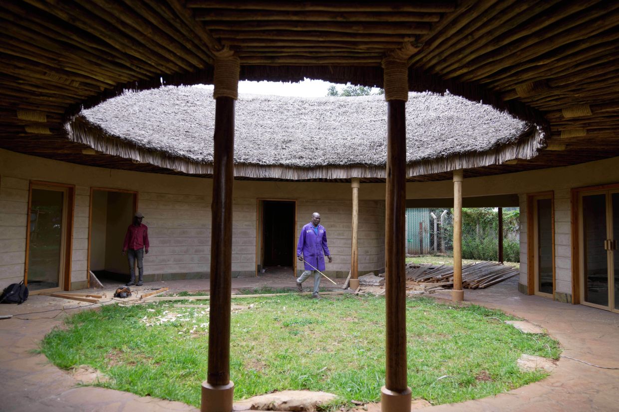 A contractor takes measurements inside a house under construction, inspecting wall and roof insulation made from agricultural waste and mushroom mycelium in Nairobi, Kenya, Friday, Sept. 12, 2025. (AP Photo/Brian Inganga)