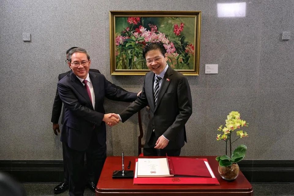 Prime Minister Lawrence Wong (right) and Chinese Premier Li Qiang shaking hands after Mr Li signed the guestbook at Parliament House on Oct 25. -- ST PHOTO: KEVIN LIM