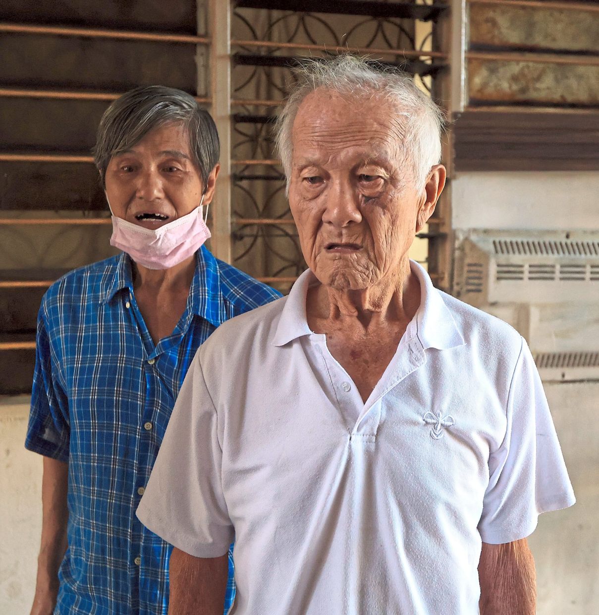 Long-time Block A residents Ho (front) and Lee say problems like leaky roofs and clogged drains should be solved first instead of putting the land up for sale.