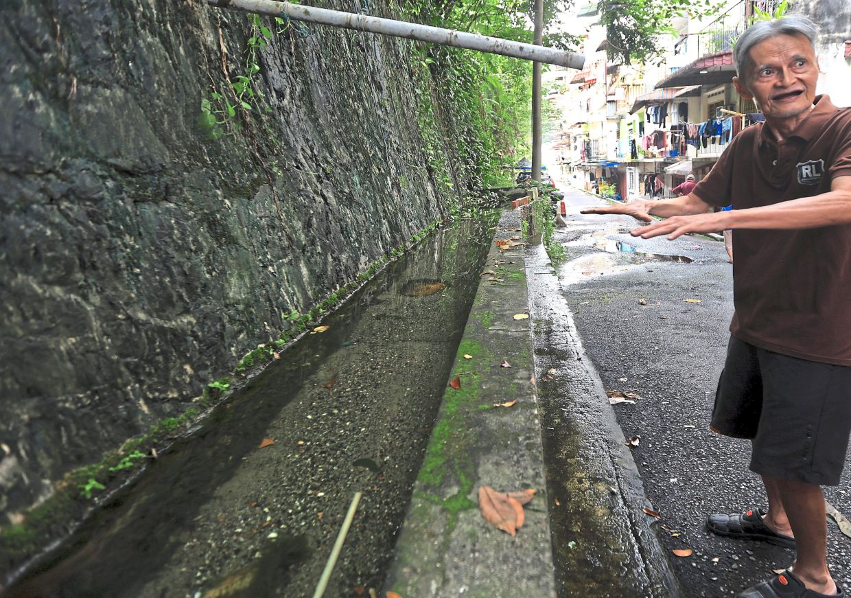 A resident showing the stagnant monsoon drain outside Block C of the flats.