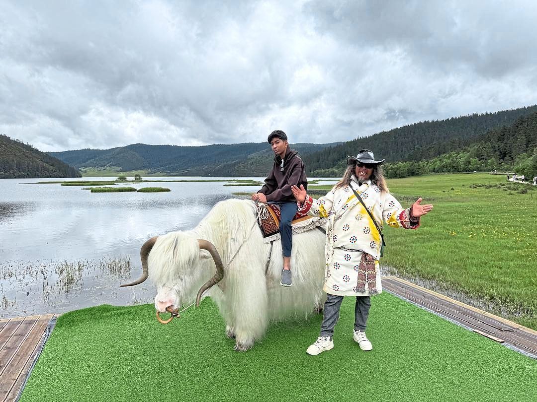 The writer’s son sitting on a white yak, while its carer sings a local song.