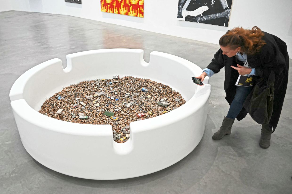A visitor photographs the artwork Schizophrenogenesis by Hirst during an exhibition tour.