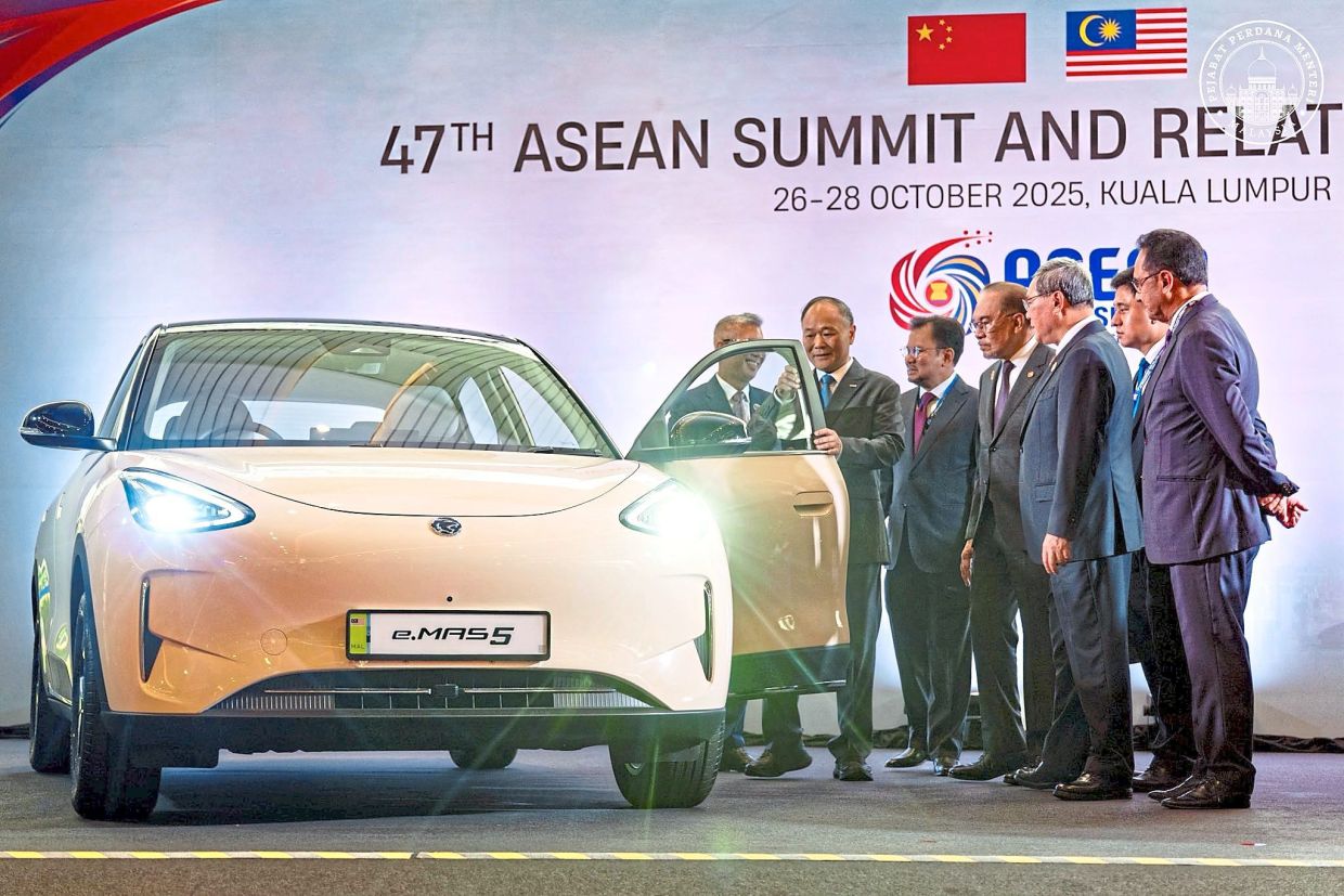 Latest wheels: Anwar and Li (third from right) viewing Proton’s new e.MAS 5 model during the summit in Kuala umpur. — Photo from the Prime Minister’s Office’s Facebook page