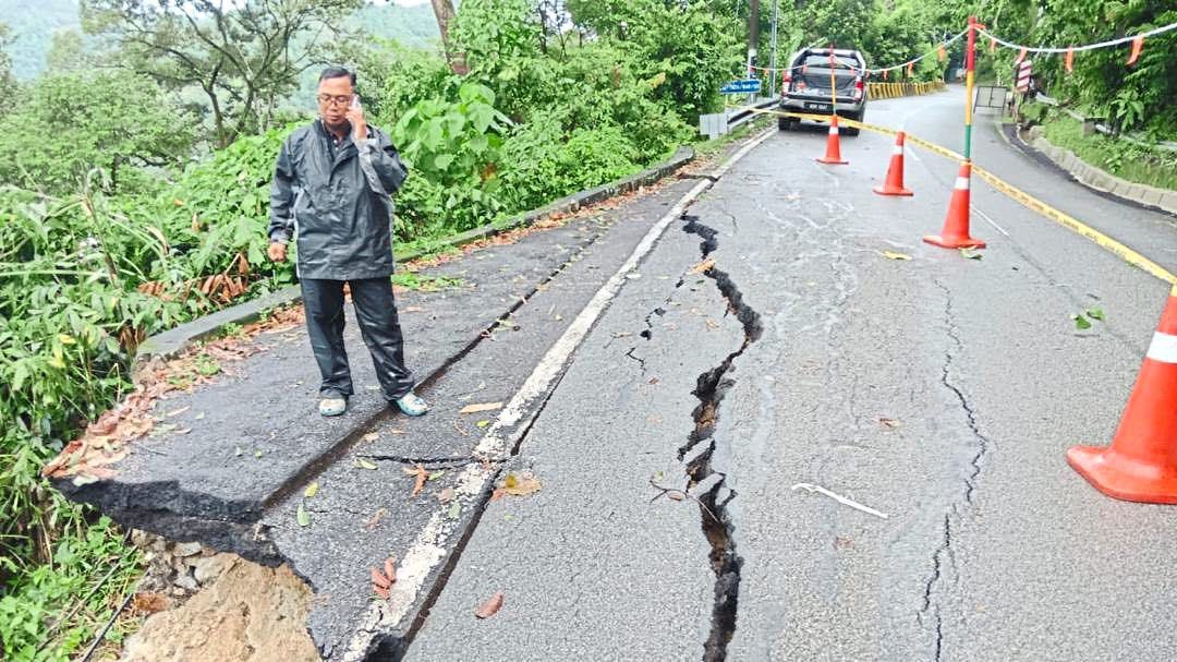 On the edge: a man standing beside a collapsed portion of the titi Kerawang road which has been affected by andslides. — Photo courtesy of Zairil Khir Johari’s social media account