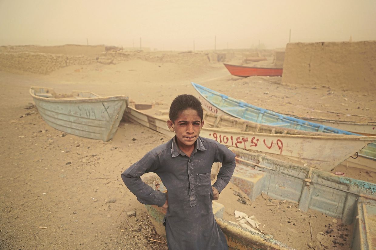 A young boy stands in front of abandonned boats where there once was a lake. The Iranian province of Sistan und Belutschistan is affected by a drought and water scarcity.