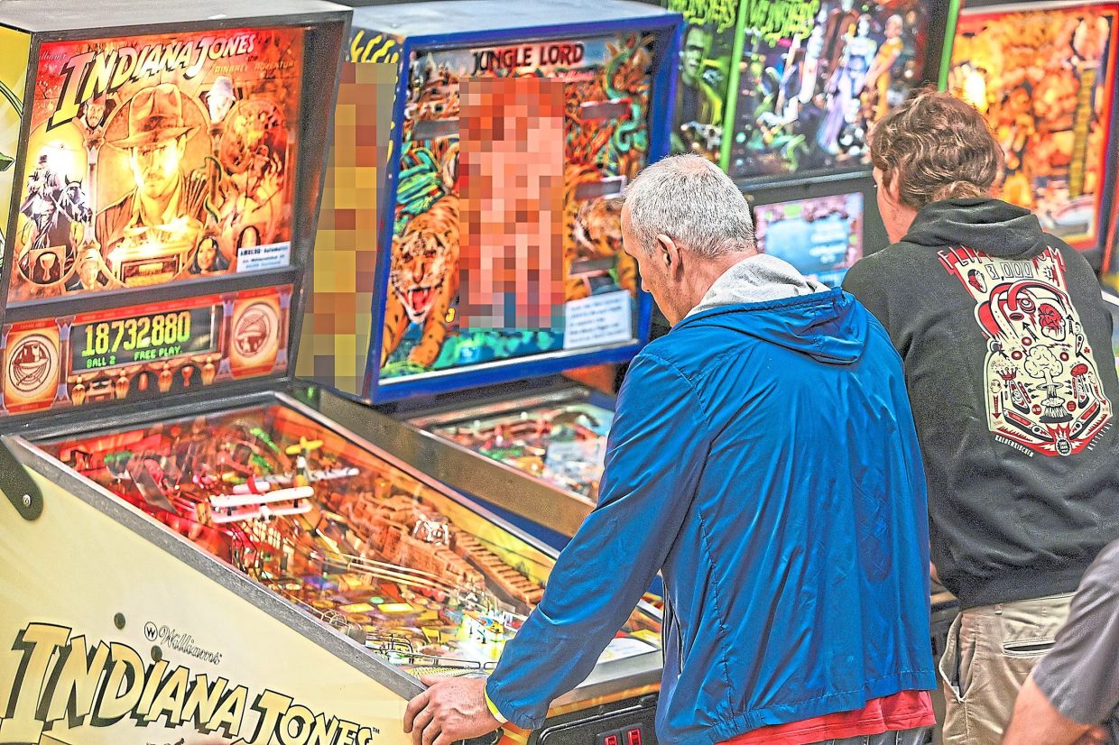 Participants stand at pinball machines on the first day of a tournament in Germany. Once written off as relics of smoky pubs, pinball machines are bouncing back. Photo: Christoph Reichwein/dpa
