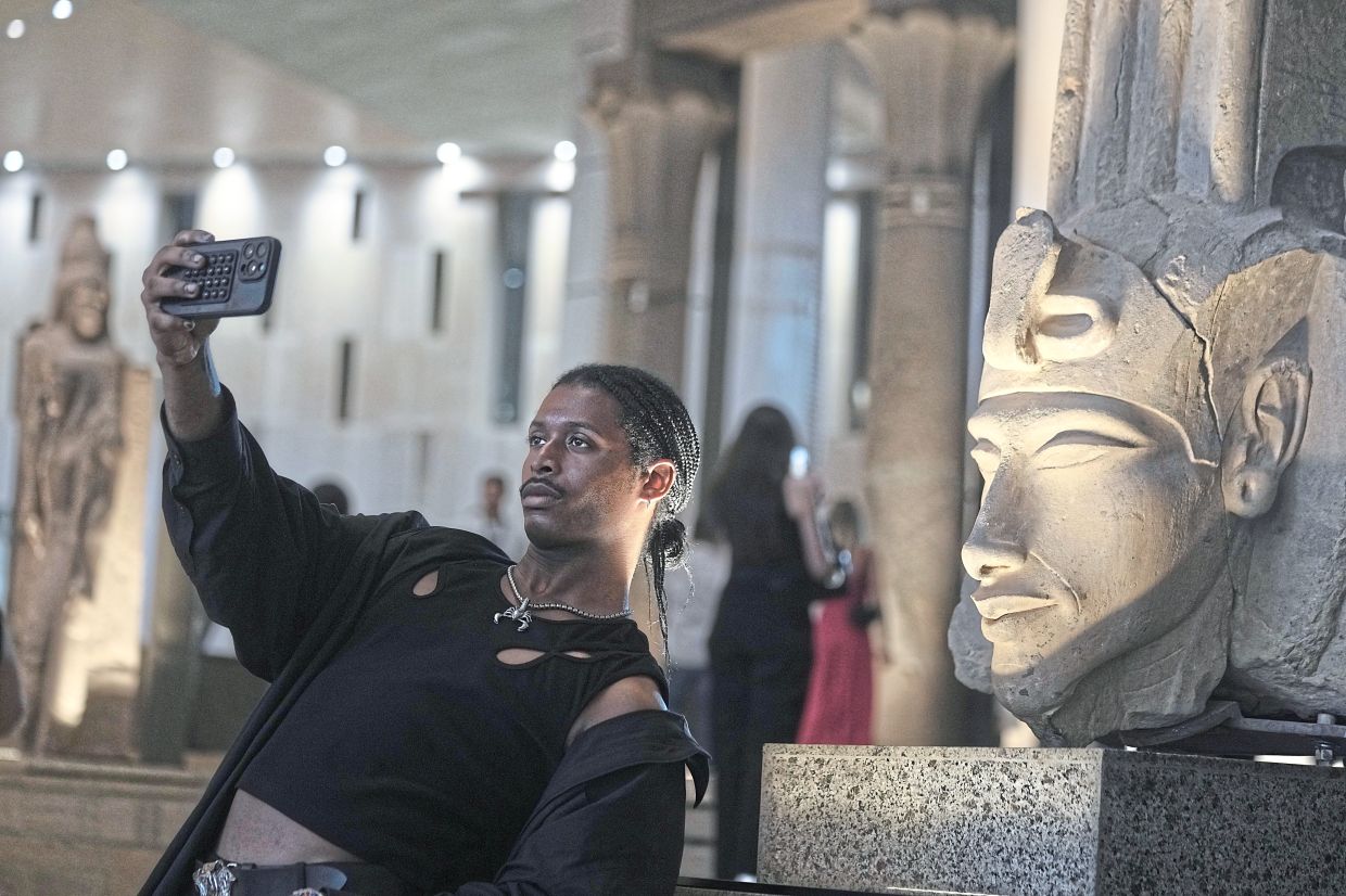 A tourist takes a selfie in front of Akhenaten statue during his visit to the Grand Egyptian Museum. Photo: AP 