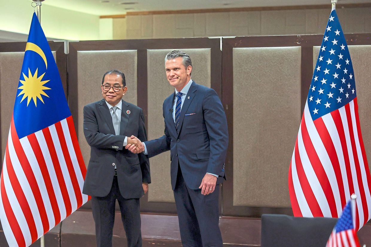 Formal partnership: Mohamed Khaled (left)shaking hands with Hegseth on the sidelines of ADMM and ADMM-Plus in Kuala Lumpur. — RAJA FAISAL HISHAN/The Star