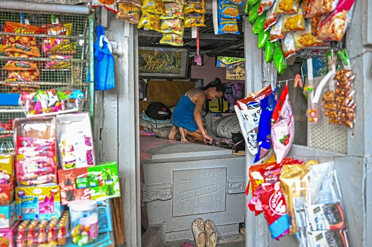 Buan cleaning her makeshift house at Manila North Cemetery. — AFP
