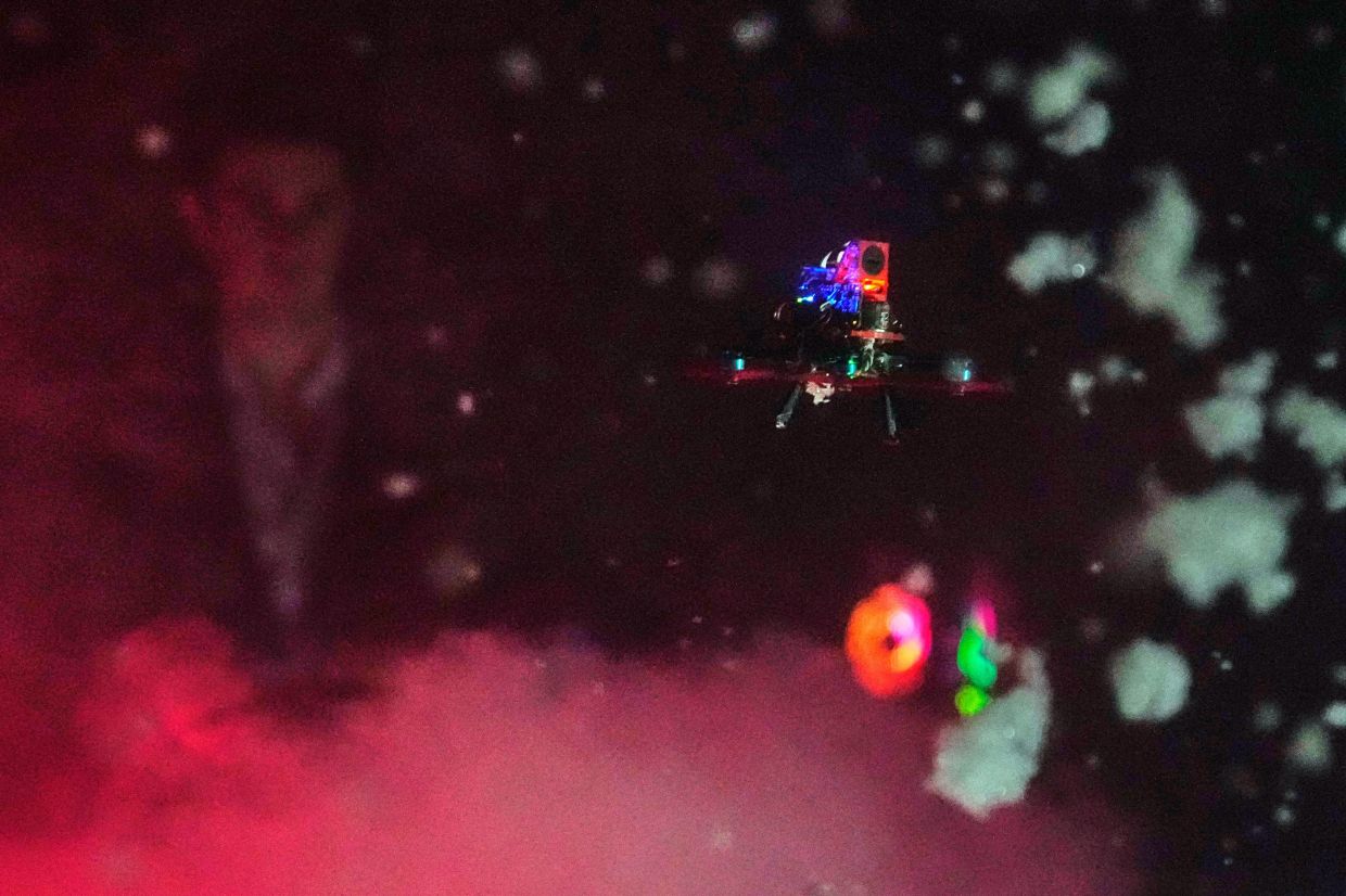 A tiny drone flies through a simulated snowstorm at night at a laboratory at Worcester Polytechnic Institute, in Worcester, Mass. — AP