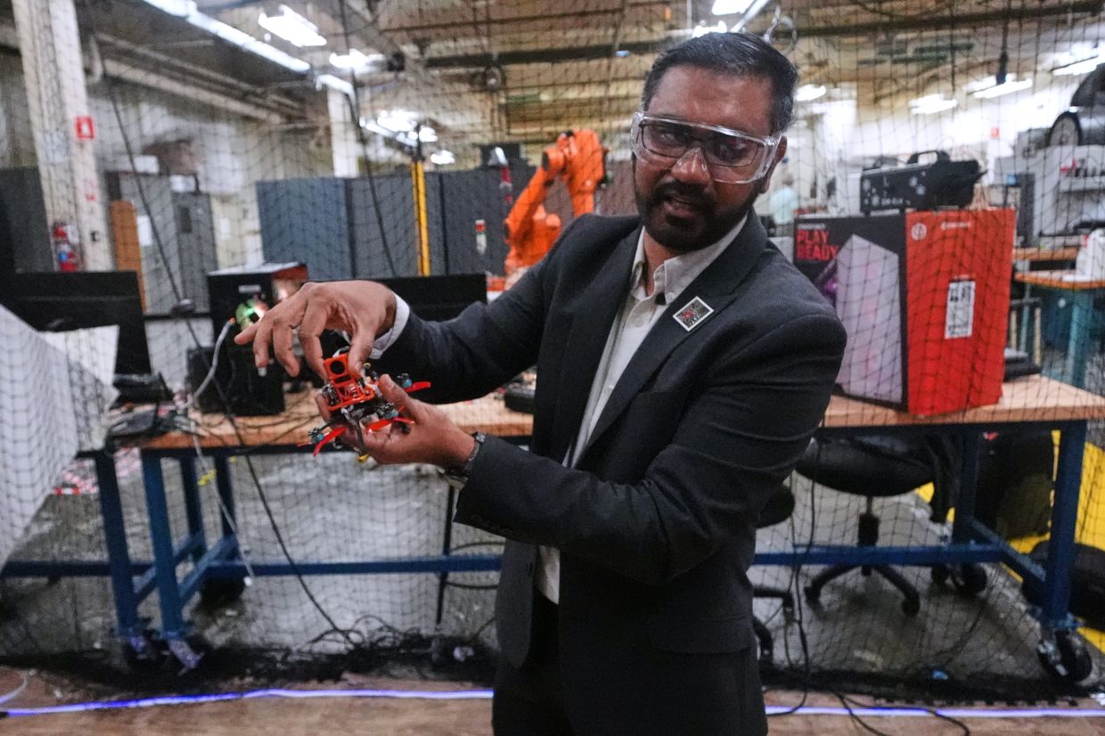Nitan Sanket, assistant professor of robotics engineering, describes the components on a tiny drone at his lab at Worcester Polytechnic Institute, in Worcester, Mass. — AP