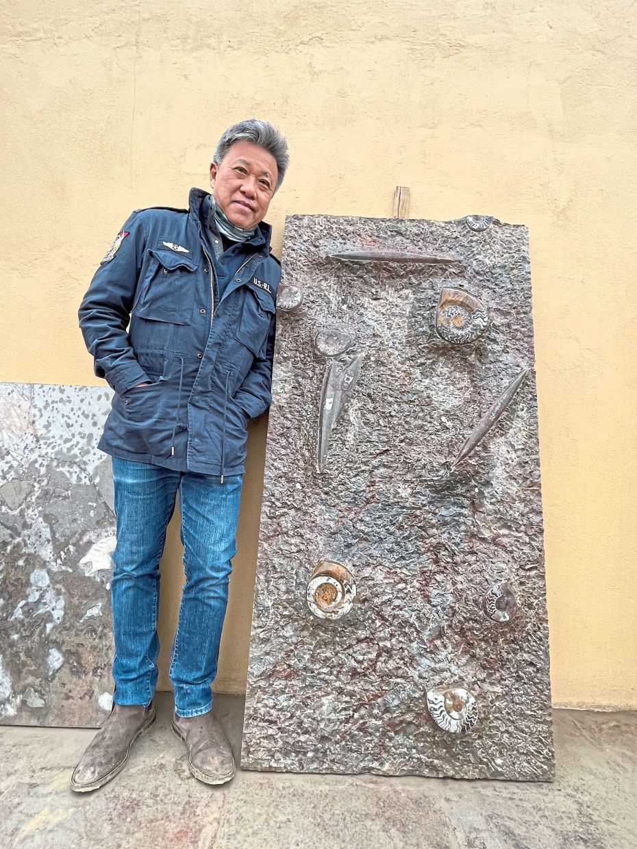 The writer standing next to a huge stone slab covered with fossils.