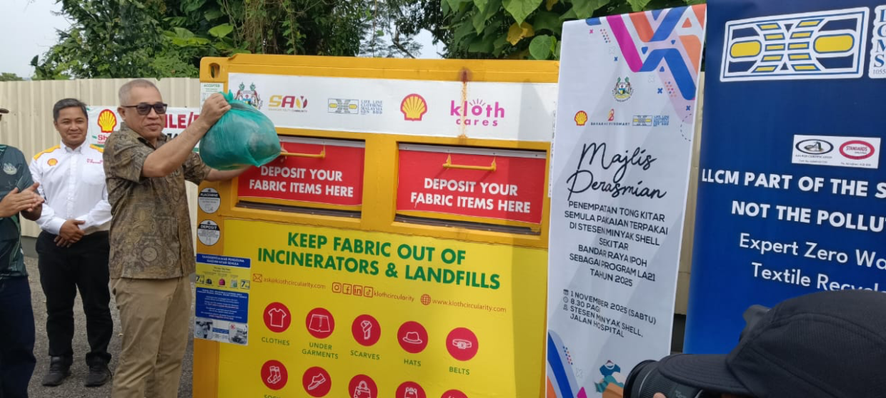 Ipoh Mayor Datuk Zamakhshari Hanipah placing a plastic of used clothing inside the newly launched clothes recycle bin at a Shell station in Ipoh.
