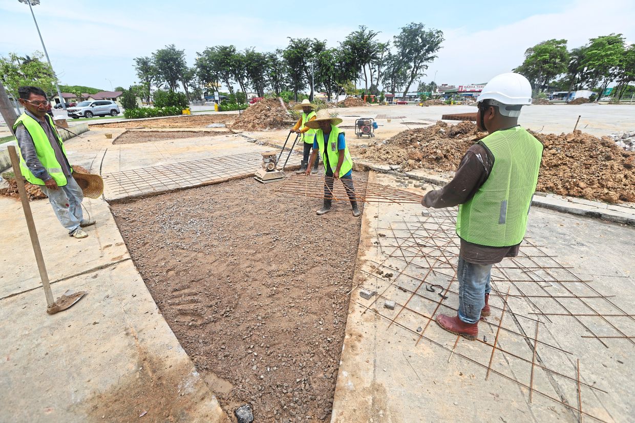 Workers preparing the grounds at Pandamaran Sports Complex to create an open space for public use.