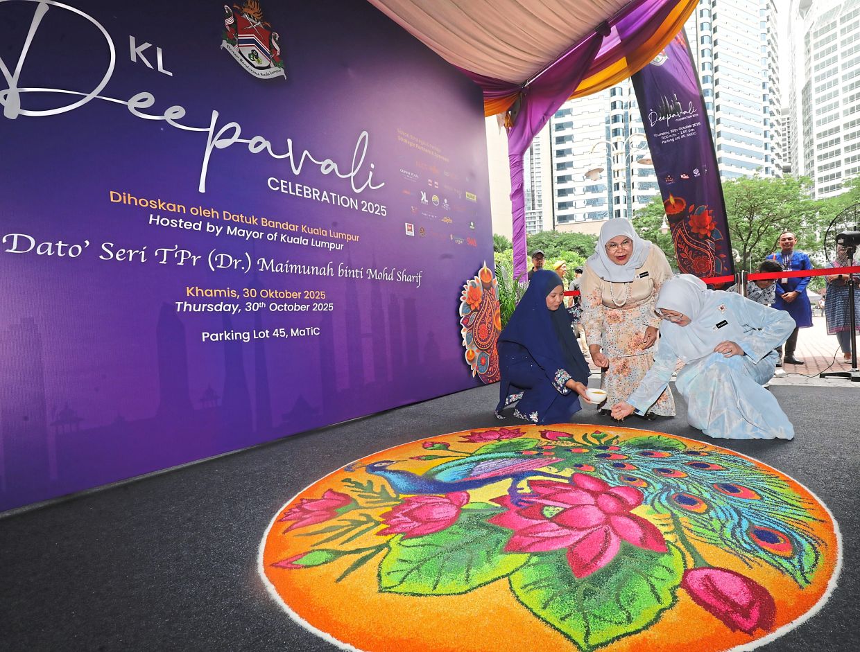 Maimunah (centre) accompanying Dr Zaliha (right) in placing the final grains of coloured rice on a ‘kolam’ to launch the Kuala Lumpur City Hall’s Deepavali celebration.