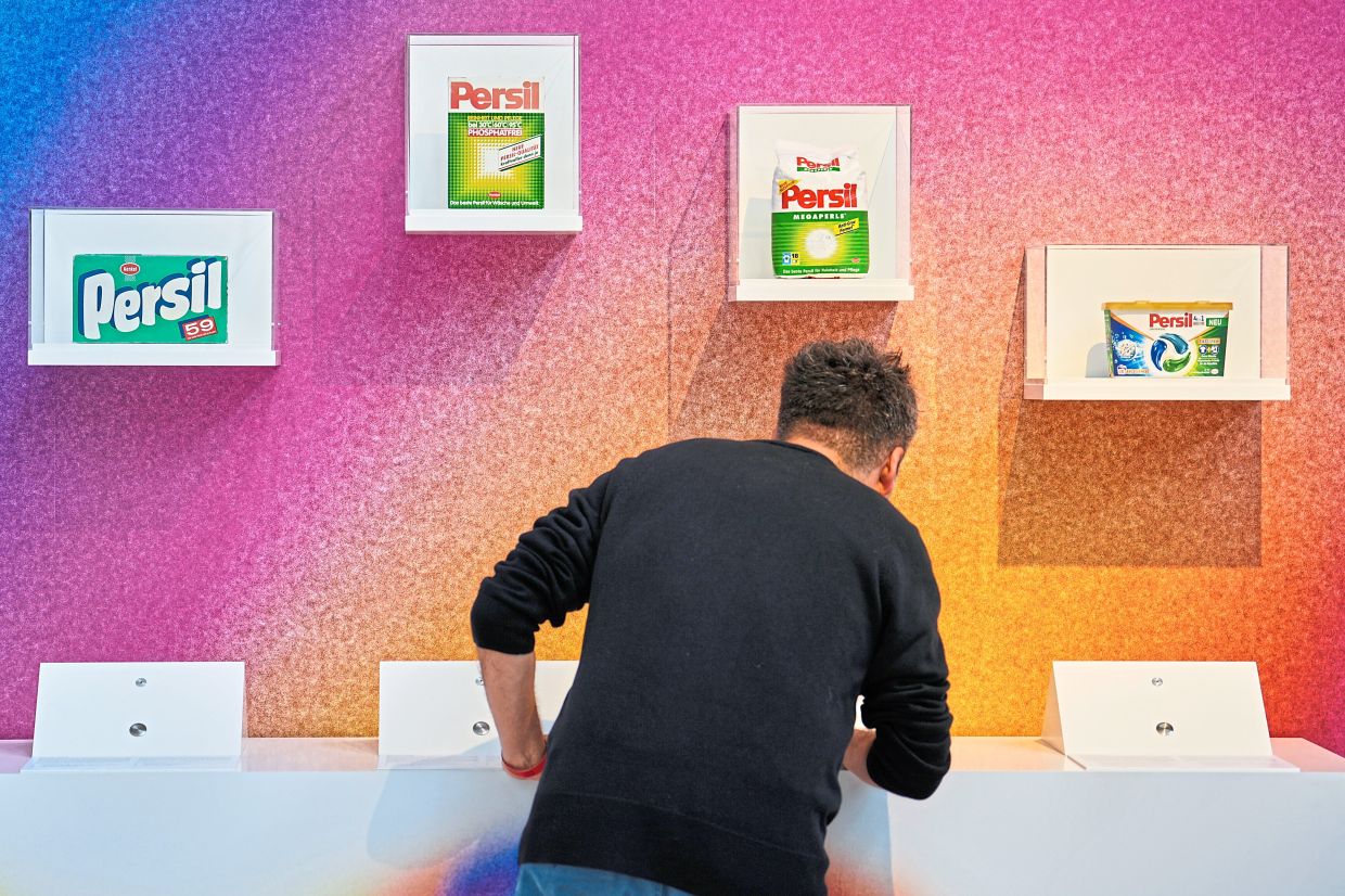 A man smells samples of different historic Persil detergent at the exhibition.