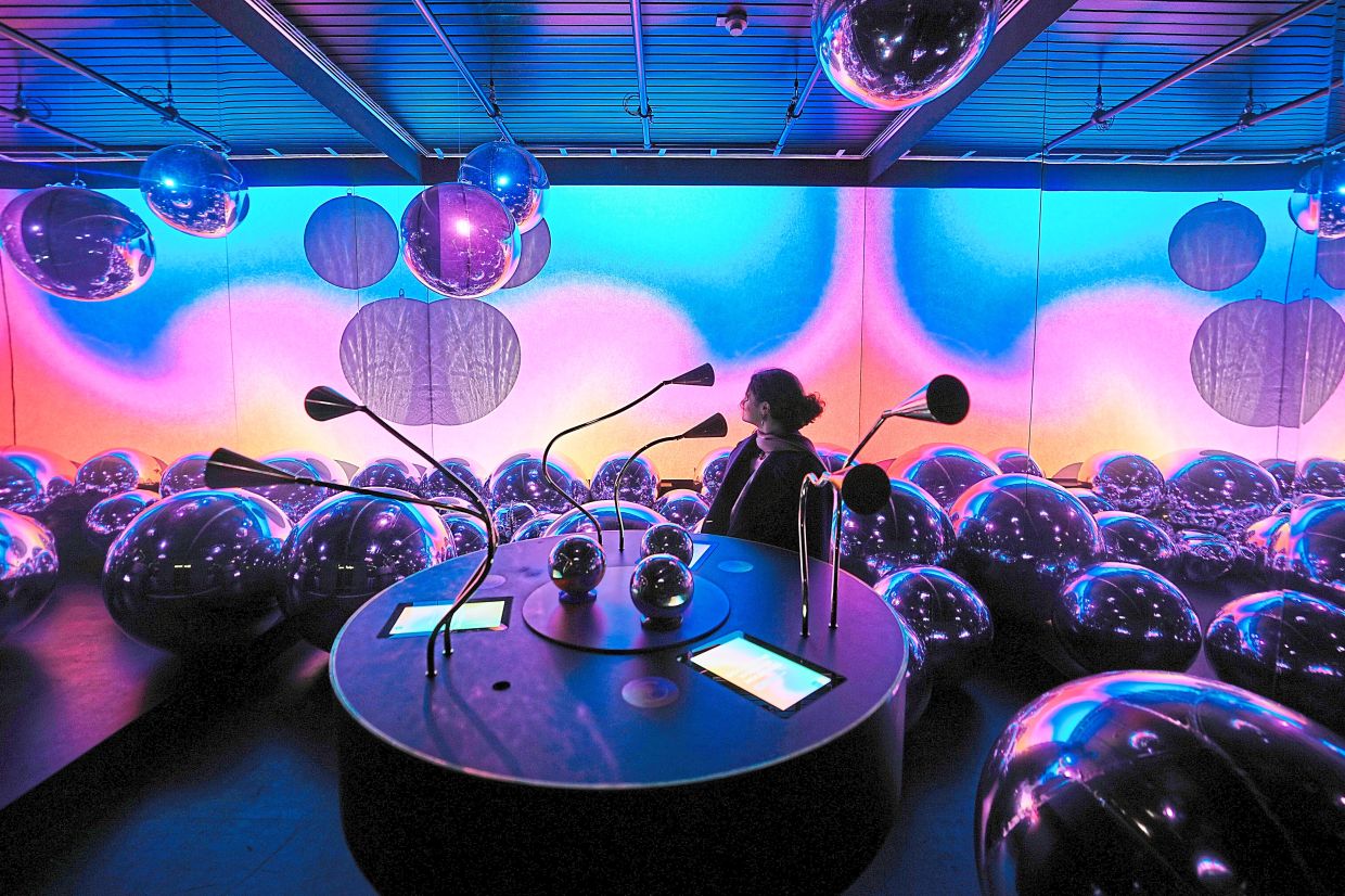 A woman explores an interactive art installation for mixing molecules that make up fragrances at the exhibition.