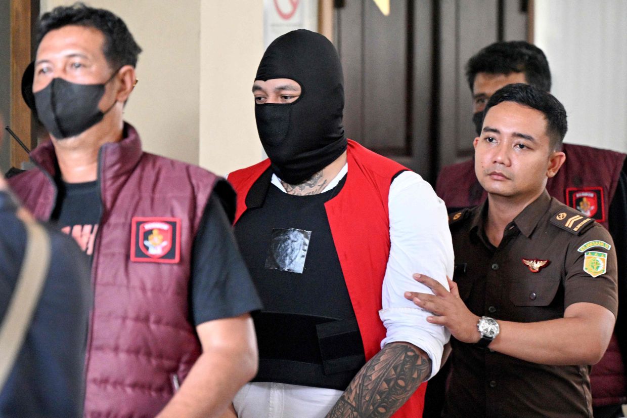Australian suspect Tupou Pasa Midolmore (left) is escorted by the police out of a courtroom after attending a hearing as part of attending his trial in Denpasar on Indonesia's resort island of Bali, on Monday, November 3, 2025. The trial of three Australians accused of plotting the murder of a compatriot at a villa in Bali began on October 30, 2025, with all facing the death penalty. -- Photo by SONNY TUMBELAKA / AFP