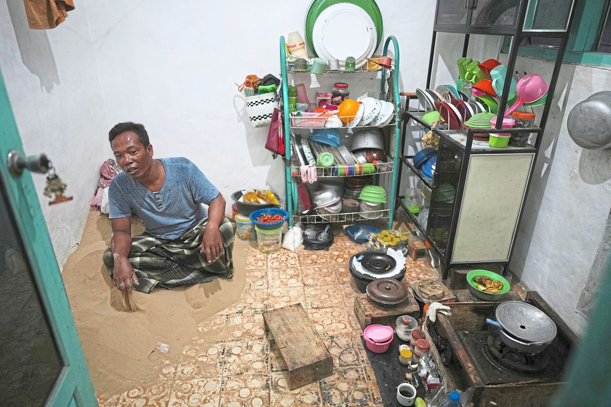 Sahnawi sits on sand in the kitchen of his house in Legung Timur village in Sumenep on Madura Island, Indonesia, Tuesday, Sept. 9, 2025. (AP Photo/Dita Alangkara)