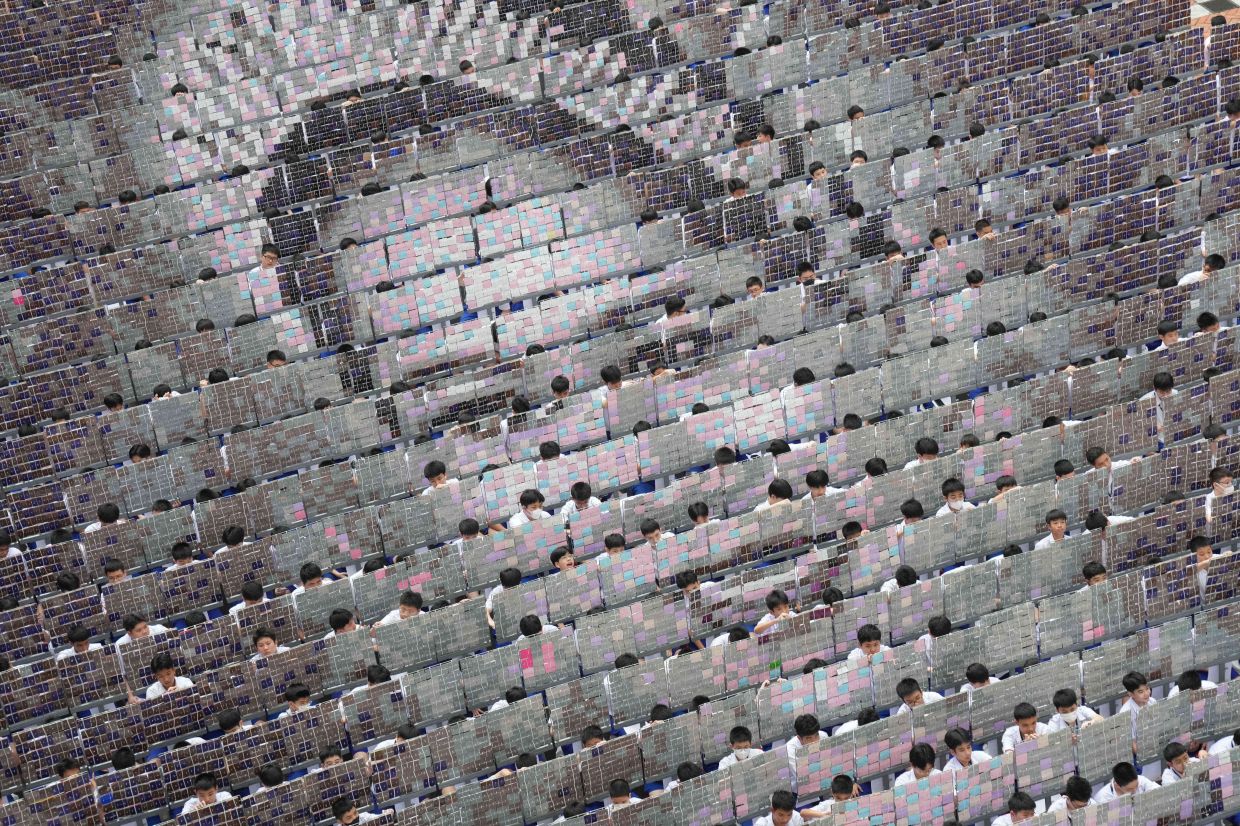 A mosaic portrait of the Queen Mother Sirikit is displayed as students practice flipping boards at Assumption College in Bangkok, Thailand. -- AP Photo/Sakchai Lalit