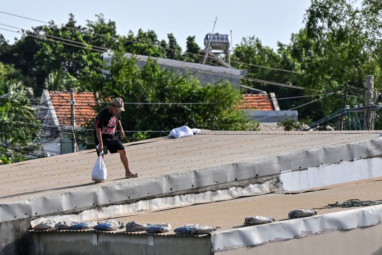 A resident reinforces the roof of a house ahead of the arrival of Typhoon Kalmaegi in Gia Lai province in central Vietnam on Wednesday, November 5, 2025. Central Vietnam, already deluged by torrential rain in recent days, is bracing for the arrival of Typhoon Kalmaegi on November 6, the national weather bureau said. -- Photo by NHAC NGUYEN / AFP