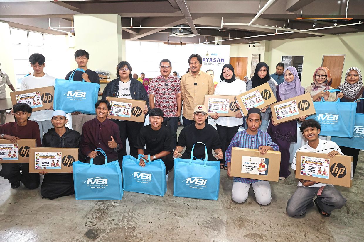 (upper row, middle, fourth left) MBI head Ahmad Azri Zainal Nor and (upper row, middle, fifth left) Selangor state executive council for youth sports and entrepreneurship Mohd Najwan Halimi with the students that received free laptops.— ART CHEN/The Star