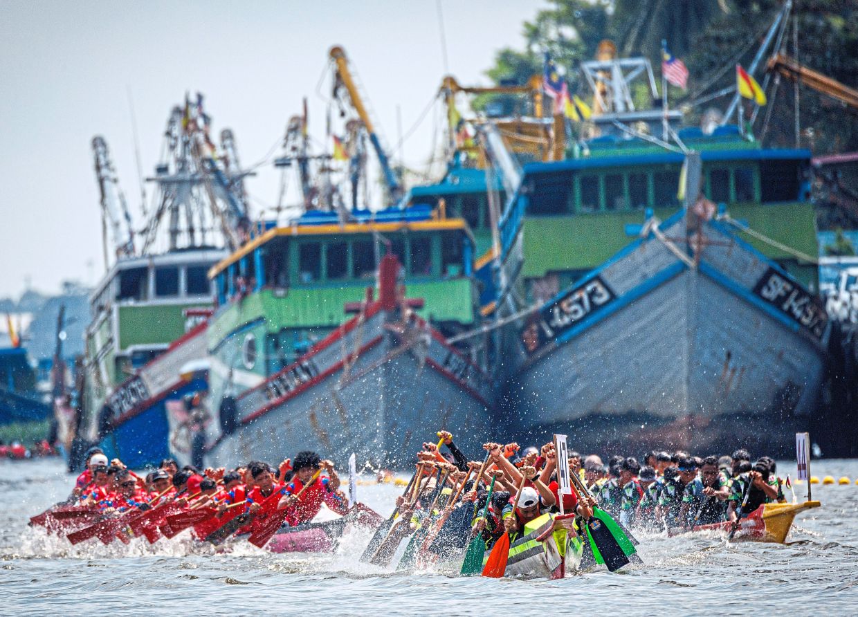 Paddlers racing past landmarks along the Kuching Waterfront. — Photos: ZULAZHAR SHEBLEE/The Star Over 60 teams took part in the Sarawak Regatta.