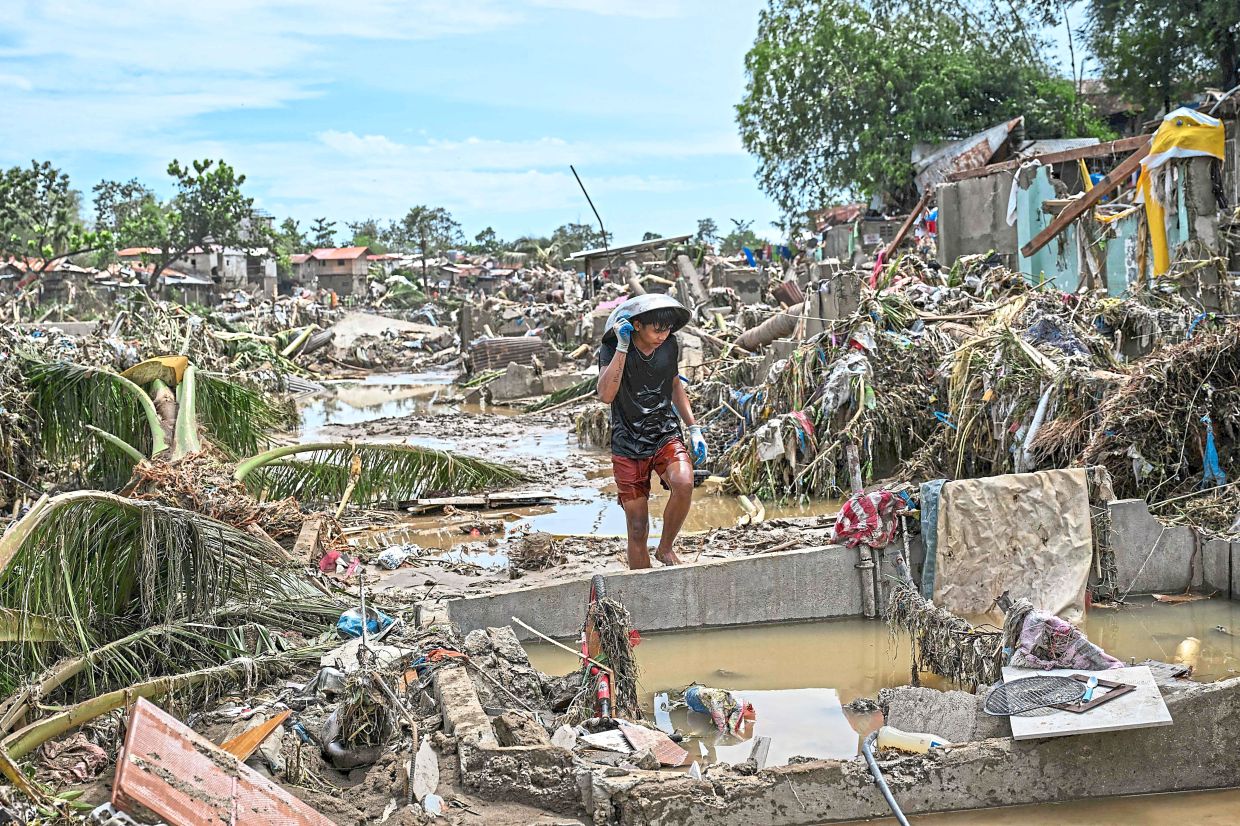 Weight of water: A resident walking along damaged houses in the aftermath of Typhoon Kalmaegi in Talisay, in the province of Cebu.