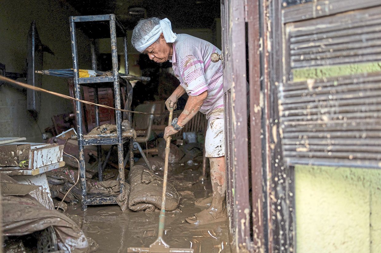  Resident Eusebio Cuyos sweeping mud out of his home in Bacayan, Cebu City. — AFP/Reuters