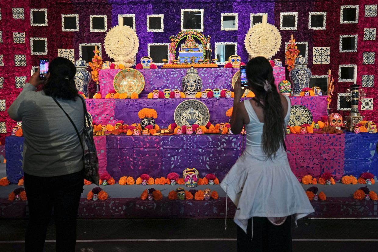 Visitors taking pictures of a Day of the Dead altar adorned with sugar skulls in Mexico City. 
