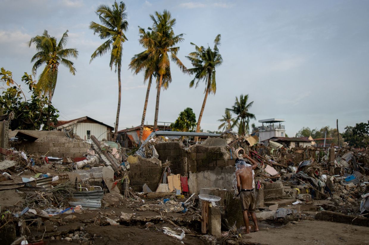 A man takes a bath amid the remains of a community where houses were swept in the floods brought on by Typhoon Kalmaegi in Talisay, Cebu, Philippines, on Thursday, November 6, 2025. -- Photo: REUTERS/Eloisa Lopez
