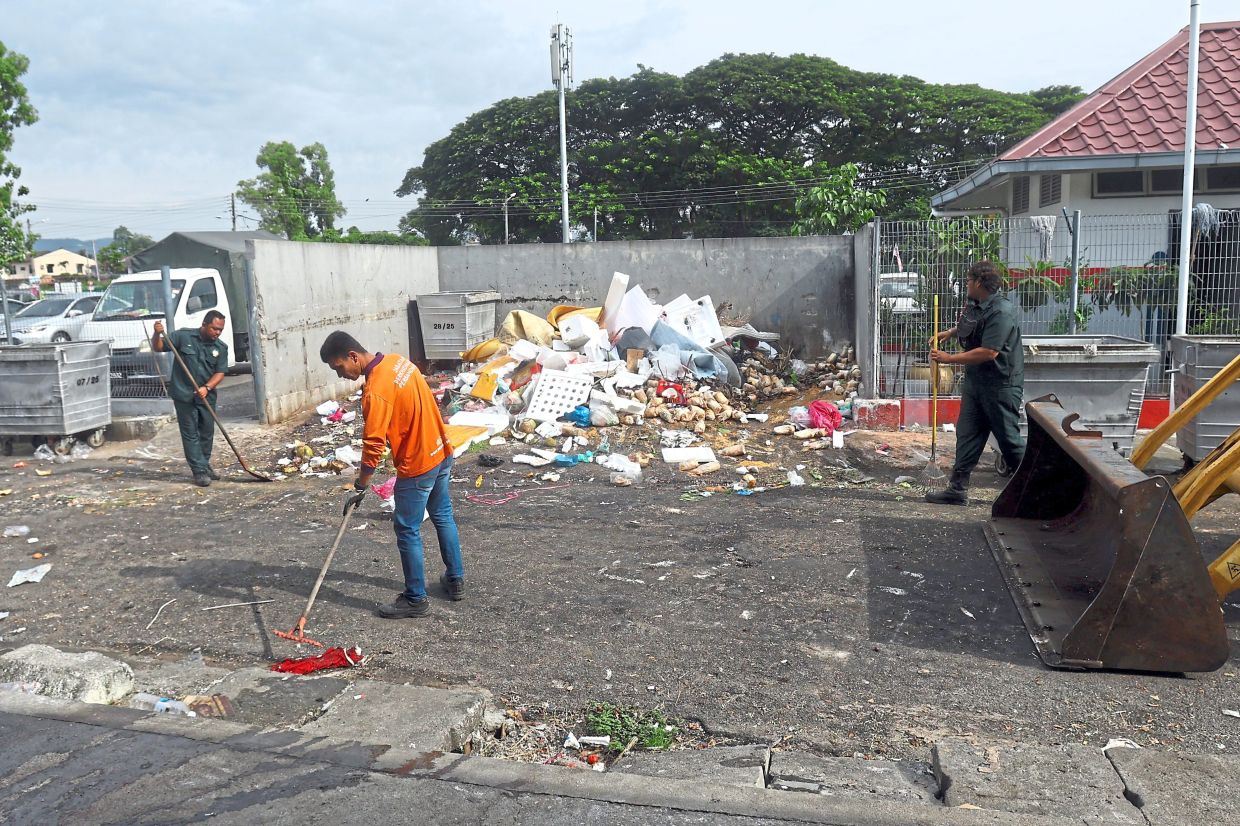 City council workers cleaning a garbage collection area at SPPK market.