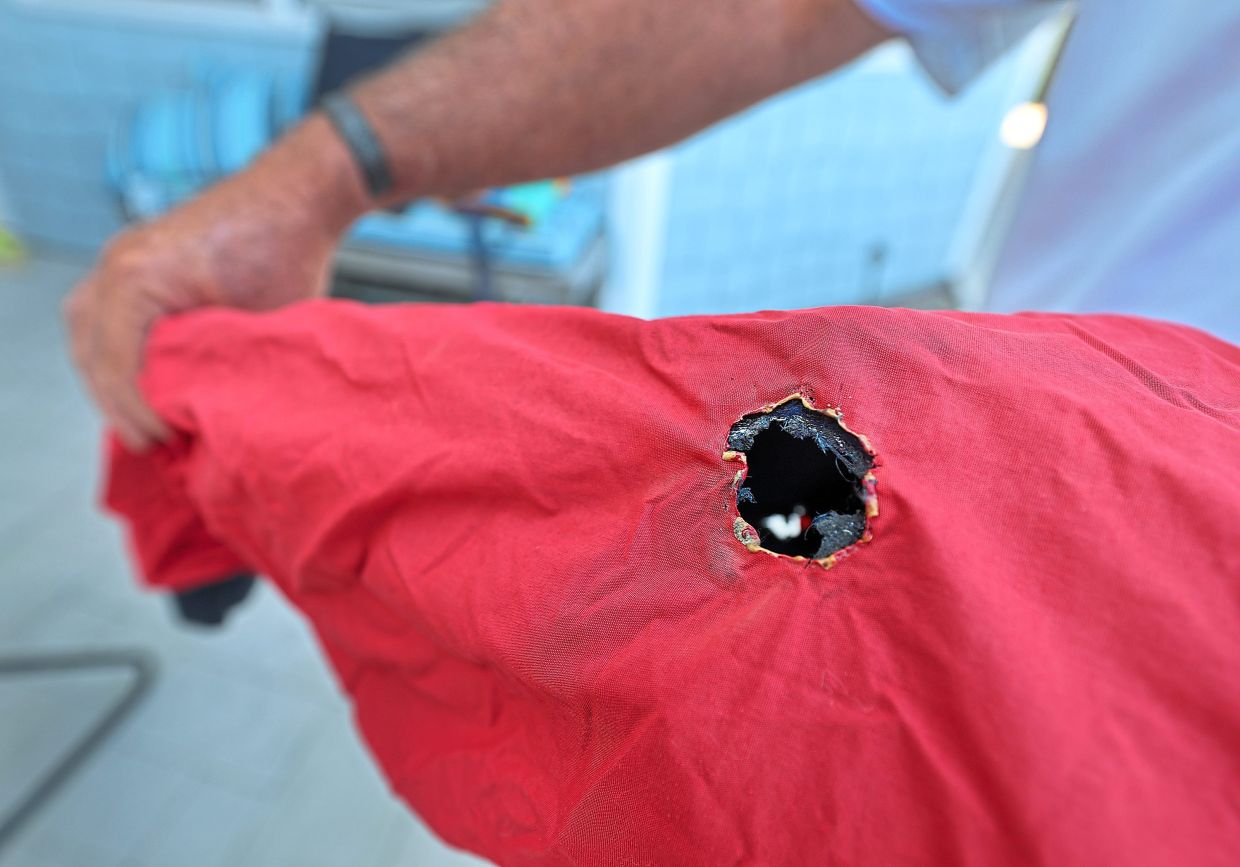 McLeod holds the jacket he was wearing, showing entry and exit holes where he was struck by lightning in a building on top of Mt Whitney 10 years ago. — Los Angeles Times/TNS