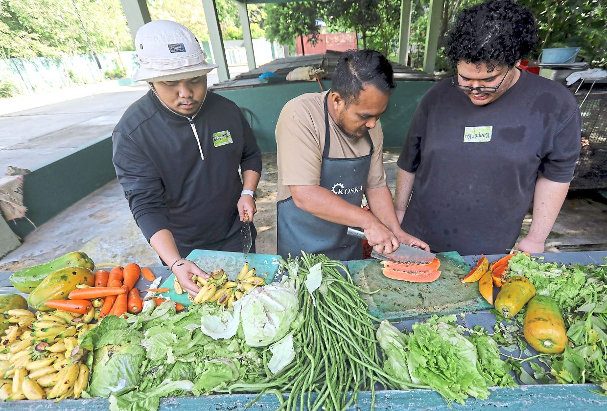 A zookeeper (centre) showing volunteers how to prepare food for the animals.