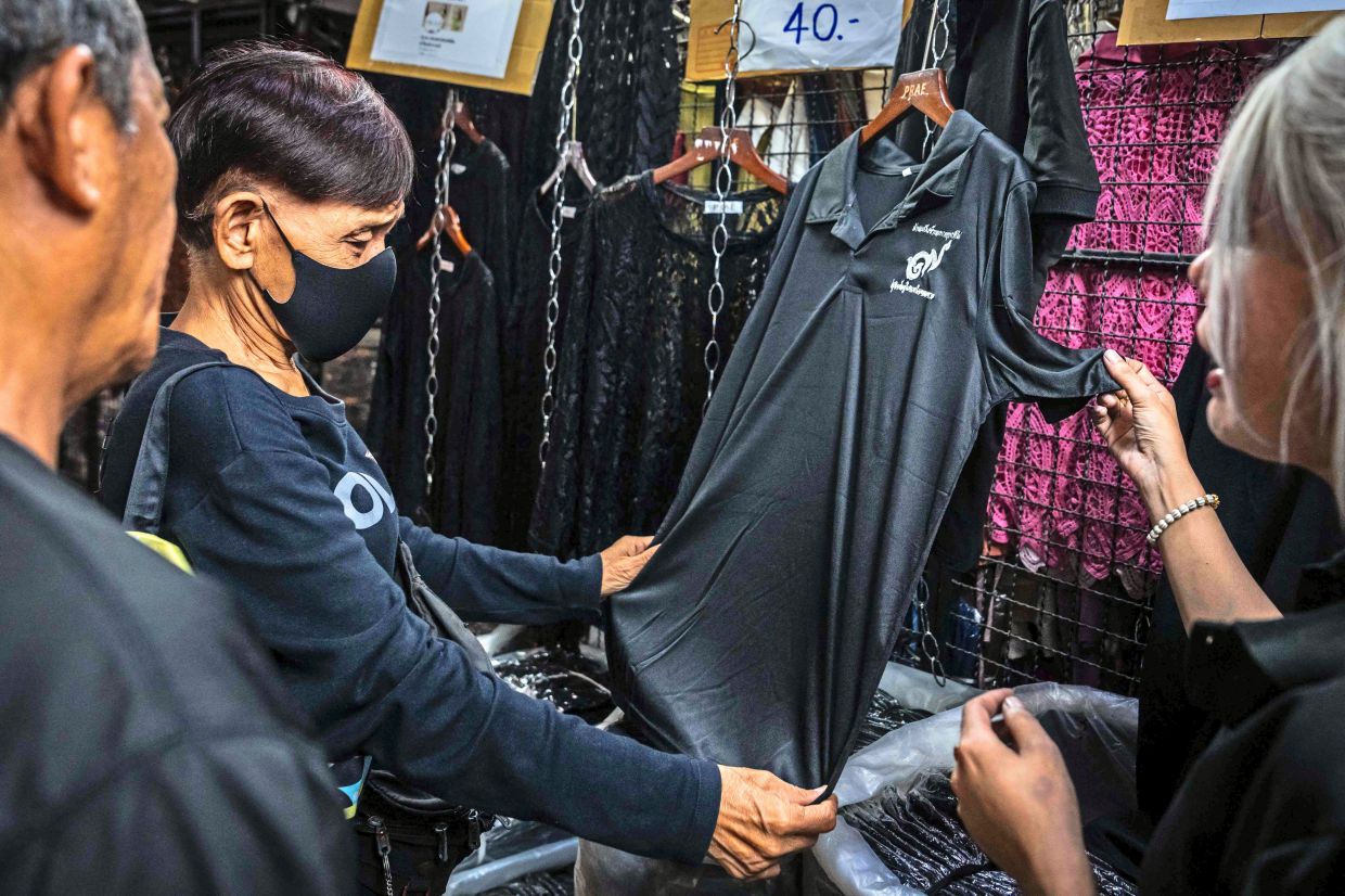 All black: Customers browsing for black clothing to mourn Sirikit’s death at a store in Bangkok. (Below) A display window at a retail store in a shopping mall in Bangkok features black and white clothing. — AFP