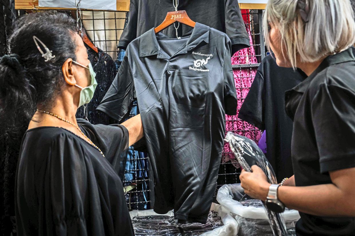 Customers browse for black clothing to mourn the death of Thailand's former queen Sirikit at a store in Bangkok on October 30, 2025. The government has declared a year-long mourning period for officials and urged the public to wear traditional Thai mourning colours of black or white for 90 days. (Photo by Chanakarn Laosarakham / AFP)