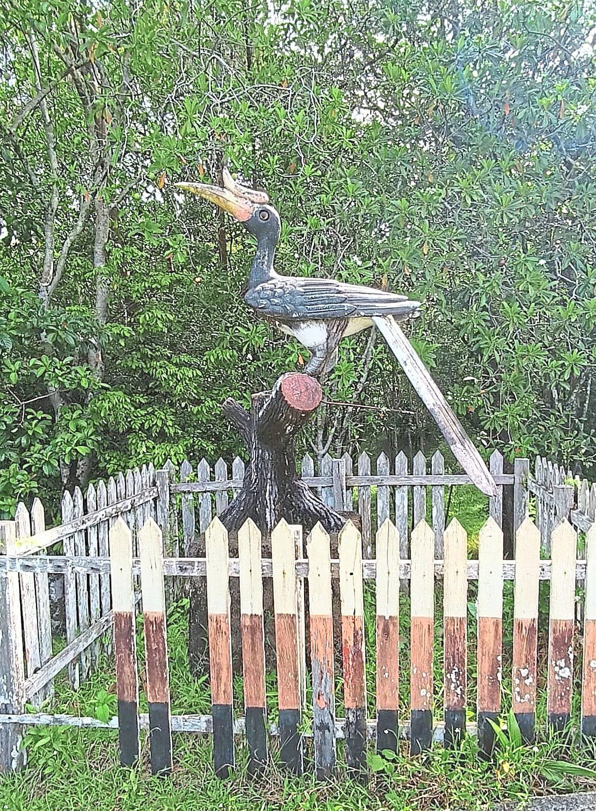 A hornbill statue with broken fencing at Sebangkoi Forest Park.
