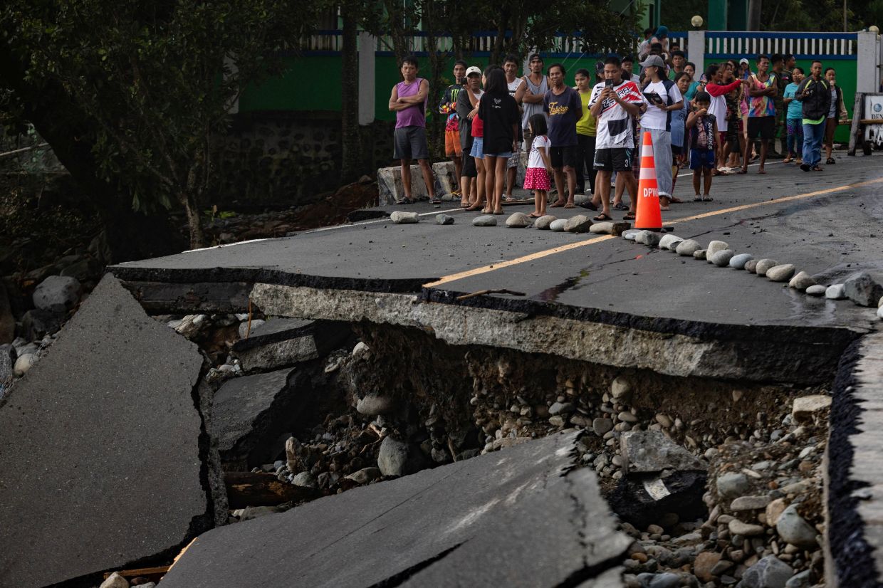 People stand near a wrecked part of the Baler-Casiguran road a day after Typhoon Fung-wong made landfall in Dipaculao, Aurora, Philippines, November 10, 2025. -- Photo: REUTERS/Eloisa Lopez