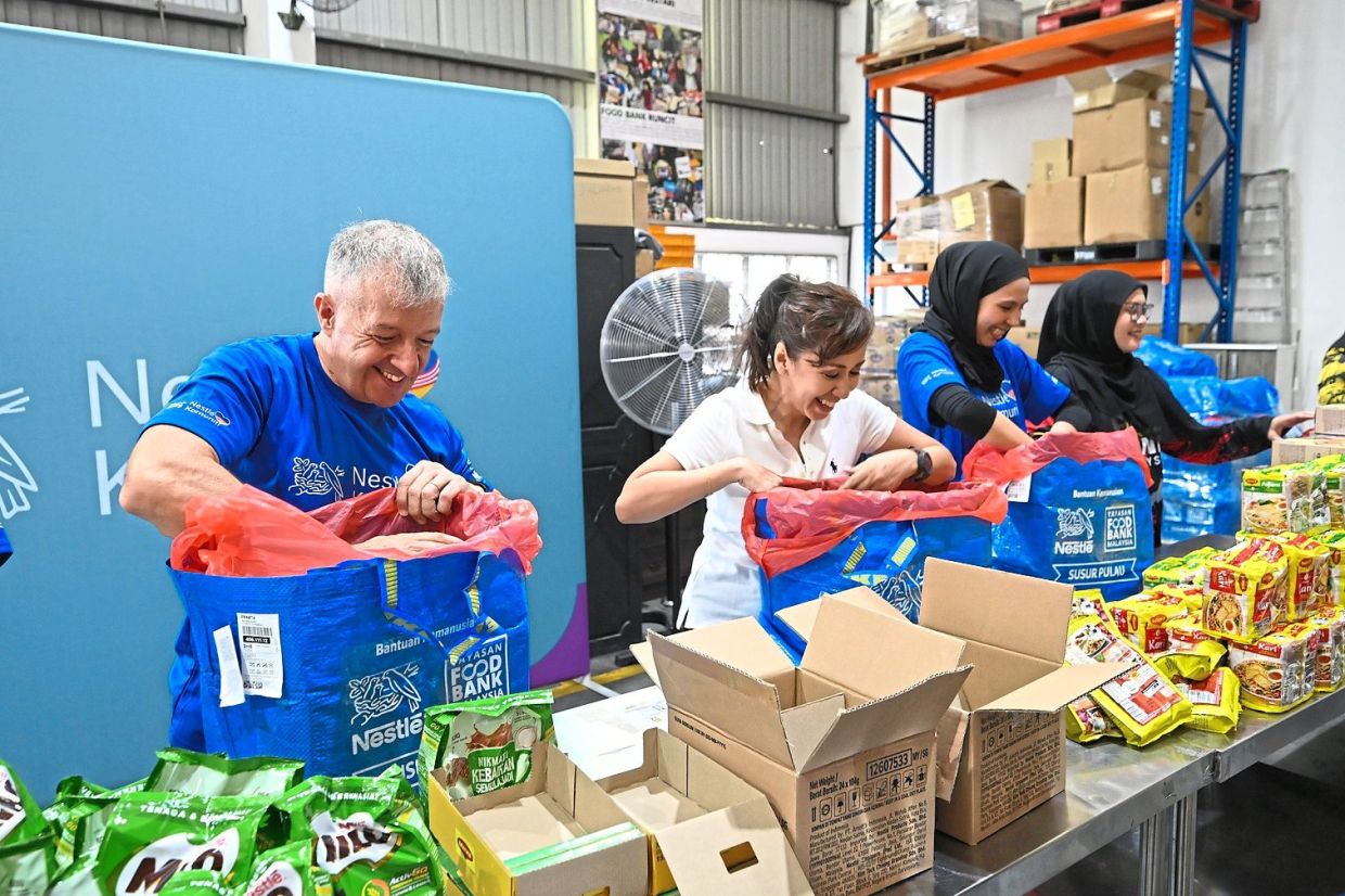 (From left) Aranols, Tengku Zatashah and volunteers packing supplies for families at risk during the monsoon season.