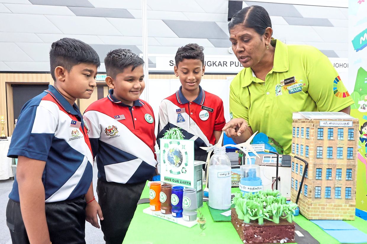 Gomathy (right) explaining to her pupils the science behind the green innovation display.