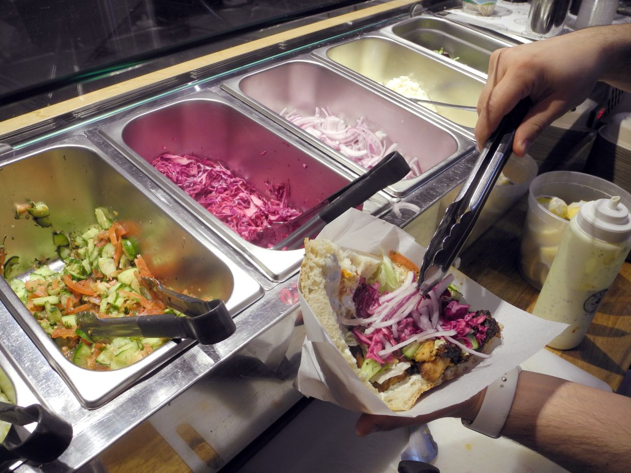 Erkan Emre, the owner of Kotti Berliner Doener Kebab in New York, prepares a doner for a customer. – Photo: Johannes Schmitt-Tegge/dpa