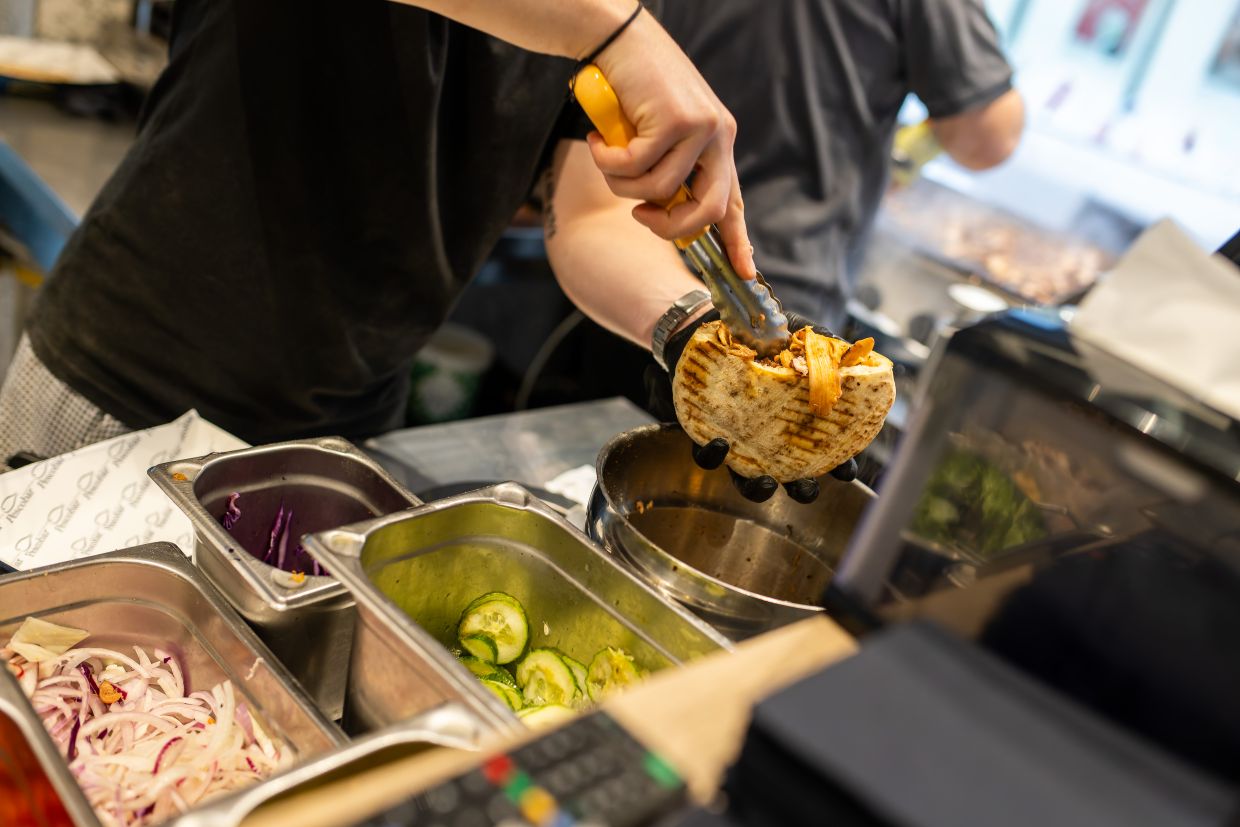 An employee prepares an Octopus Doener sandwich at the 'Pescobar' restaurant in Karlsruhe. Photo: Philipp von Ditfurth/dpa