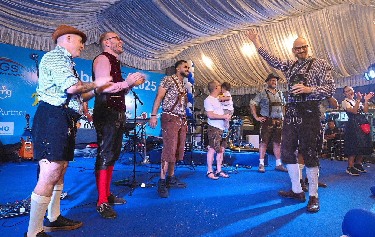 Lederhosen-clad guests parading on stage for the best dressed award at the event.