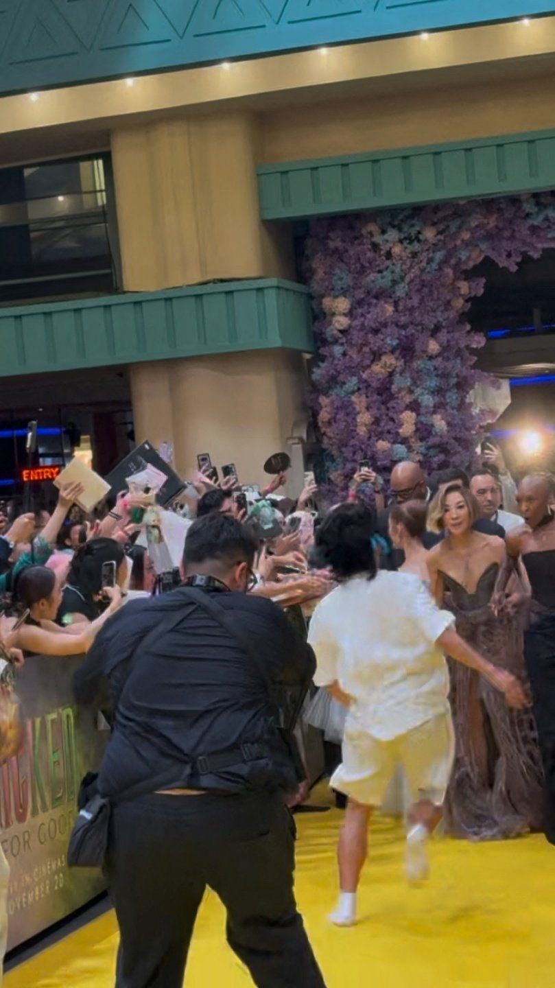 A fan who jumped a barrier runs towards Ariana Grande as she walks the carpet alongside cast members Michelle Yeoh and Cynthia Erivo during the 'Wicked: For Good' movie premiere in Singapore. Photo: Reuters