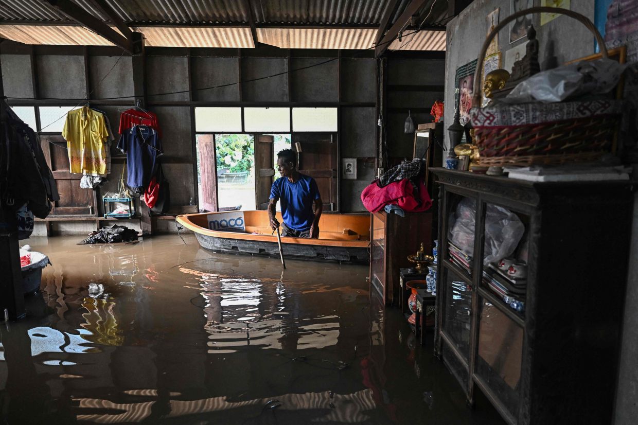 Thai retiree Somkid Kijniyom, 69, sits on a boat inside his flooded home in Bang Ban district.- AFP